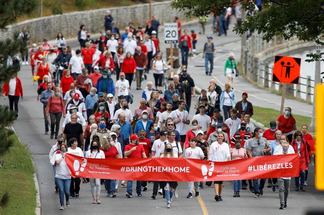 约有数百人聚集在渥太华的一处公园，手持「#把他们带回家」的标语。(图／路透社)