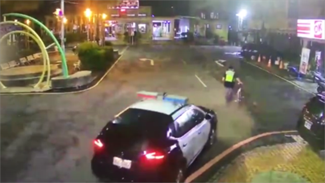 少年独自在二水街头徘徊，员警护送他回警所等家长接回，监视器画面录下二水分驻所警员刘钊宏牵着少年脚踏车返回所内的身影。（警方提供／谢琼云彰化传真）