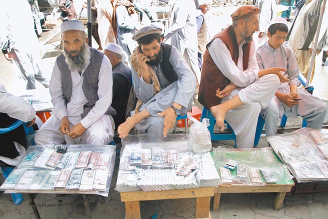 阿富汗喀布爾貨幣交易市場4日重新營業，圖為貨幣兌換商人在喀布爾一處貨幣交易市場內，等待顧客上門。（新華社）