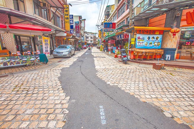北埔老街石板路中間舖了一長條的柏油，被遊客戲稱像貼「狗皮膏藥」。（羅浚濱攝）