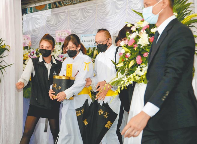 李行女儿李显顺（中）昨神情哀伤捧着牌位送行。（陈俊吉摄）