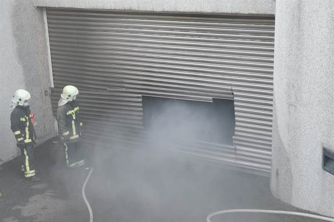 新竹县政府地下停车场发生轿车自燃火警，地下室铁卷车自动下降，启动防火阻隔机制，消防局因此用电锯切开让浓烟排出。（罗浚滨摄）