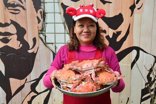 捕蟹船主太太手捧一盤剛蒸好的萬里蟹，邀請大家來產地買萬里蟹，拍攝時非疫情期間。（新北市漁業處提供）