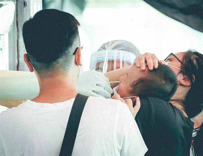 新北市板桥幼儿园爆发群聚事件，家长10日带着小朋友前往江子翠筛检区，小孩採检不适露出痛苦表情，家人在一旁安抚。（罗永铭摄）