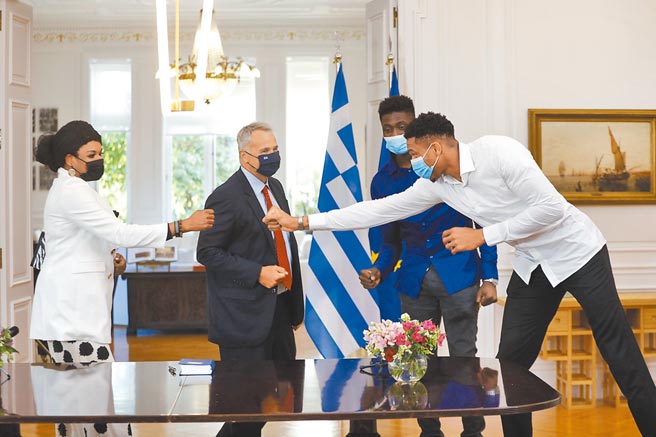 希臘總理米佐塔基斯（左二）接見公鹿球星「字母哥」阿提托康波（右一），親自授予字母哥的母親維羅妮卡（左一）、小弟艾力克斯希臘國籍，字母哥還逗趣的在總理面前跟母親擊拳慶祝。（美聯社）