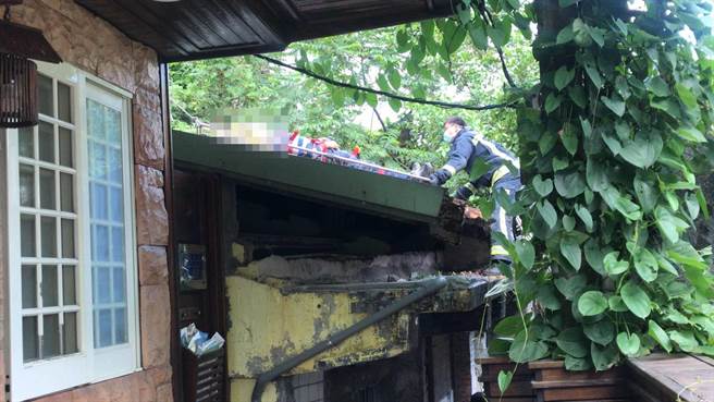 消防人员架梯爬上一旁废墟铁皮屋合力将男子救下。（陈彩玲摄）