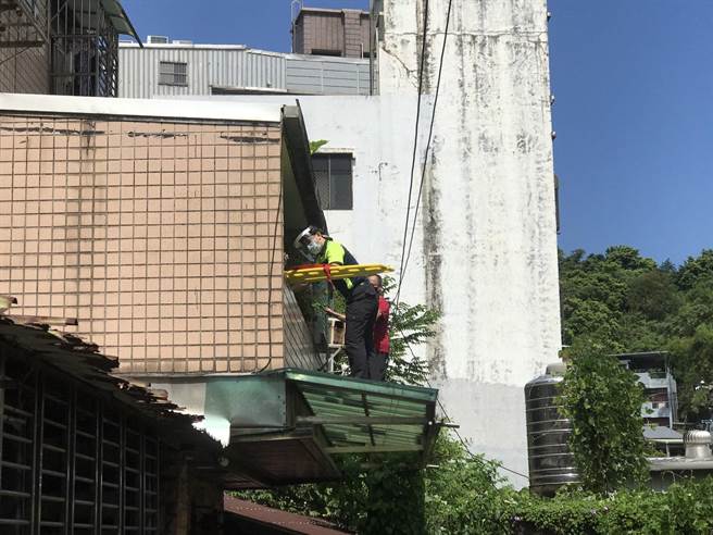 救护人员从二楼住家递送长背板。（陈彩玲摄）