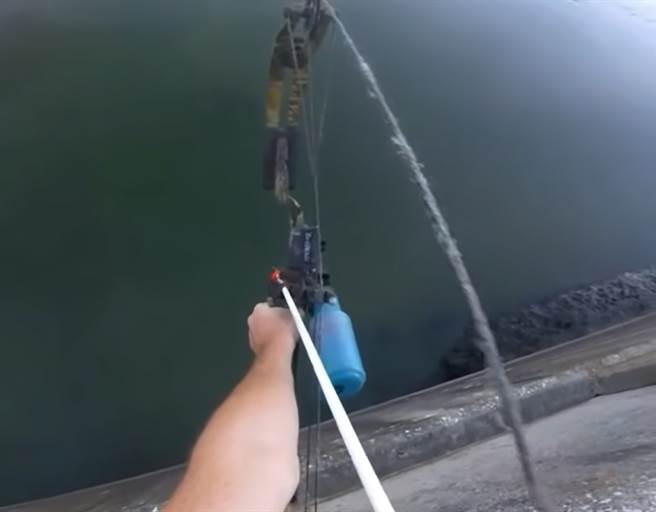 男子站在水坝上，拿着弓箭射向水面下的鱼，没想到竟一次命中，神准度震惊无数网友。（图片翻摄自YT/stephen banaszak）
