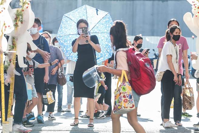 明天（22日）各地天氣多雲到晴，降雨午後局部短暫雷陣雨為主，花東有36度高溫發生機率。圖為連假出遊民眾開心拍照。（粘耿豪攝）