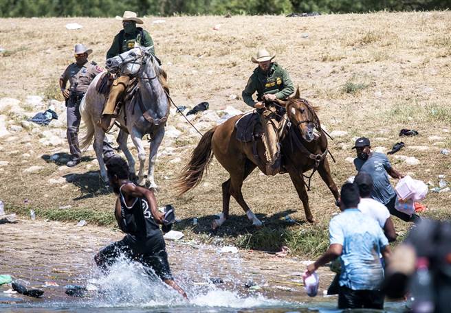 美国与墨西哥的边境近期涌入大批来自海地的移民，边境巡逻骑警骑马驱赶移民退回墨西哥河岸。（图／美联社）