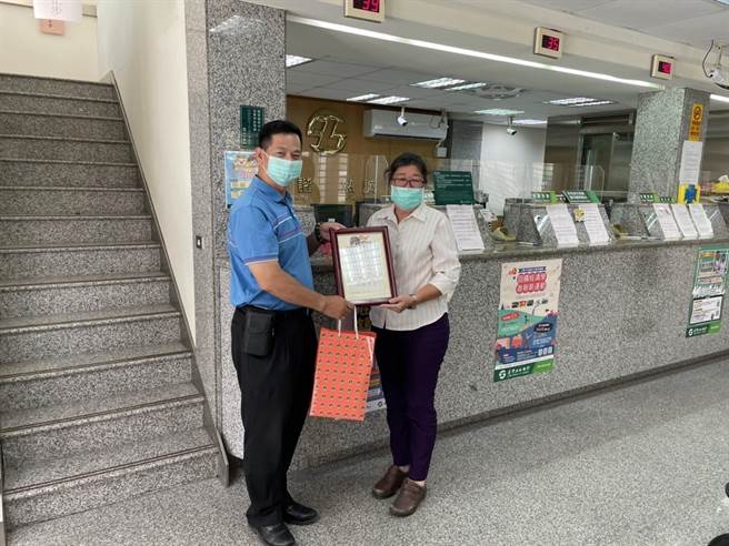 金湖分局長林炎巨贈牌給土地銀行金門分行新市里辦事處行員陳文怡，感謝在第一線把關阻詐。（警方提供）