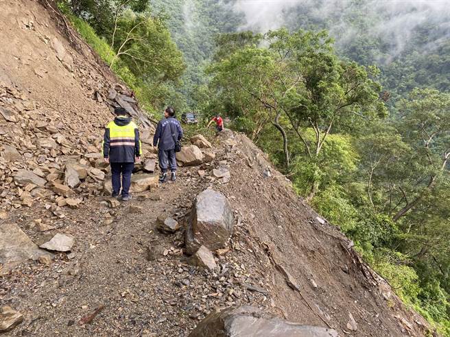 张男(红衣)因林道发生边坡坍塌阻断道路，仅差几公尺就遭土石活埋，消防局派员前往救援后，直到22日下午救难人员才顺利辟出道路，将张男救出。(林宏聪翻摄)