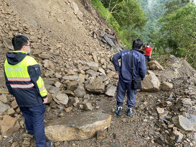 张男(红衣)因林道发生边坡坍塌阻断道路，仅差几公尺就遭土石活埋，消防局派员前往救援后，直到22日下午救难人员才顺利辟出道路，将张男救出。(林宏聪翻摄)