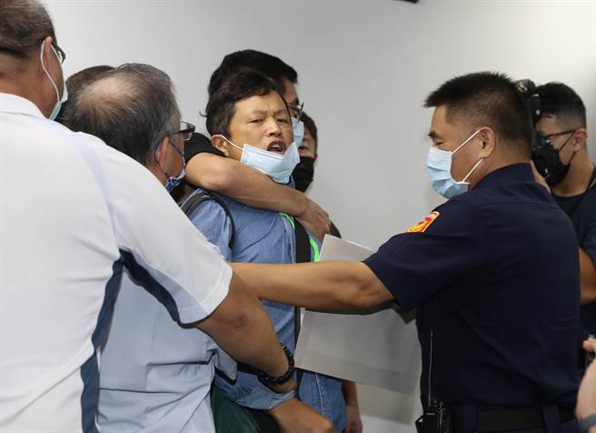 國民黨主席當選人朱立倫27日到新北市議會謝票，當朱立倫接受媒體聯訪時，一名男子（中）突然高舉標語喊叫，直指朱就是消滅中華民國的人，現場人員及駐衛警趕緊將該男子請出會場。（劉宗龍攝）