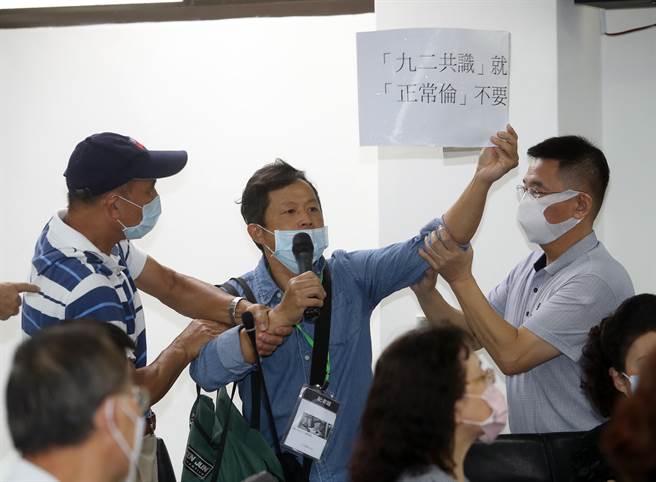 國民黨主席當選人朱立倫27日到新北市議會謝票，當朱立倫接受媒體聯訪時，一名男子（中）突然高舉標語喊叫，直指朱就是消滅中華民國的人，現場人員及駐衛警趕緊將該男子請出會場。（劉宗龍攝）