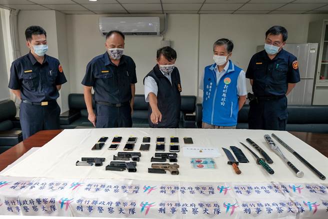 新竹县警局展现扫黑成果，县刑大大队长陈荣标（中）向县警局长吴敬田（右二）说明，查获5把改造手枪等黑帮犯罪工具。（罗浚滨摄）