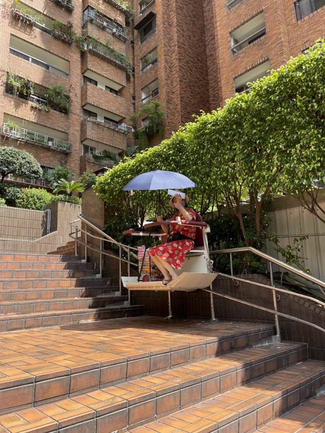 台北市議員李慶元指出，由於電梯被該建設公司控制住，民眾出入只能被迫走露台樓梯，行動不便者只能搭軌道式爬梯機。（北市議員李慶元提供）