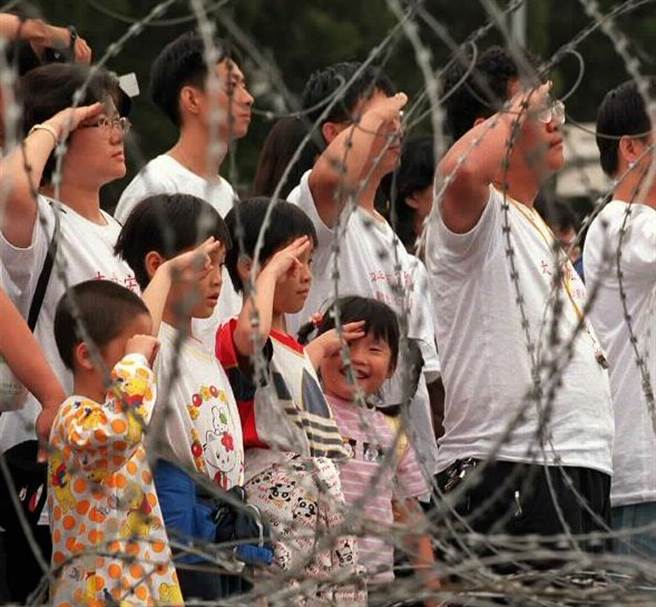 受921影响当年取消国庆庆祝活动，921受灾联盟则在总统府前隔着蛇笼，以举手礼向国旗致敬，度过一个不一样的双十国庆。（姜永年摄）