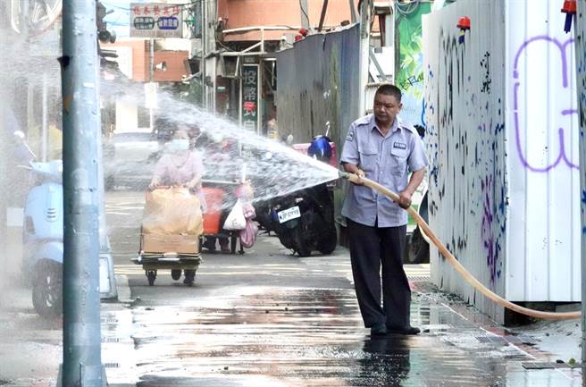劳动部长许铭春29日在立法院针对基本工资调幅表态支持调涨，指出各方对调涨基本工资都有共识和期待。台北的一处工地警卫在下班前洒水清理周边道路。（陈信翰摄）