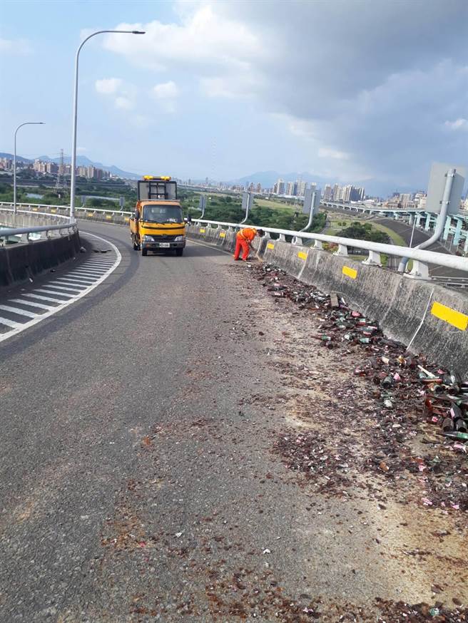 新北市土城區陳姓男子今下午2時許駕駛曳引車由城林橋上台65引道往國道方向，未料行經轉彎處，疑似車上捆繩斷裂，導致大量啤酒玻璃瓶散落。（警方提供）
