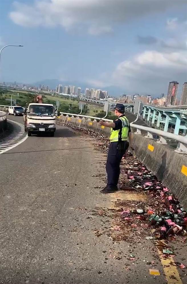 新北市土城區陳姓男子今下午2時許駕駛曳引車由城林橋上台65引道往國道方向，未料行經轉彎處，疑似車上捆繩斷裂，導致大量啤酒玻璃瓶散落。（警方提供）