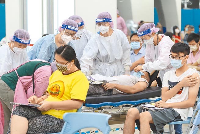 台北市的长庚注射站，29日替民眾接种新冠疫苗，有民眾在接种BNT疫苗后感不适，由大批医护人员照料休息。（陈俊吉摄）