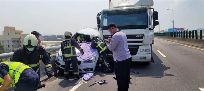 一台BMW小客车疑因故停靠路边，后方大车不慎追撞侧夹小客车，消防人员紧急协助驾驶脱困。（台中市消防局提供）