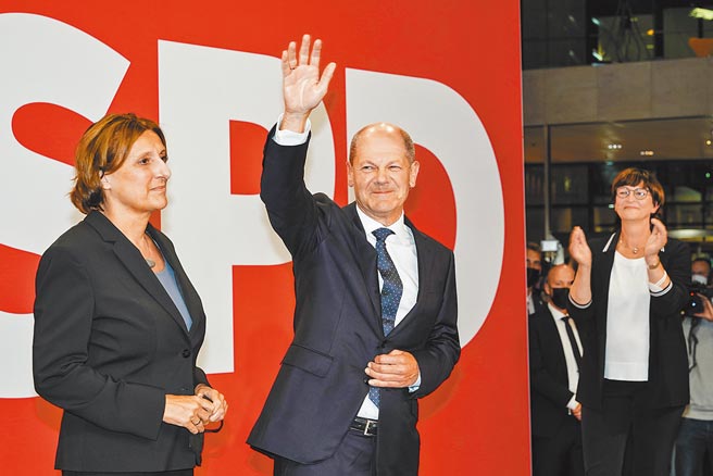 德国社民党日前在联邦议院选举中得票率居冠，社民党总理候选人萧兹（中）在首都柏林社民党总部，向支持者挥手致意。（新华社）