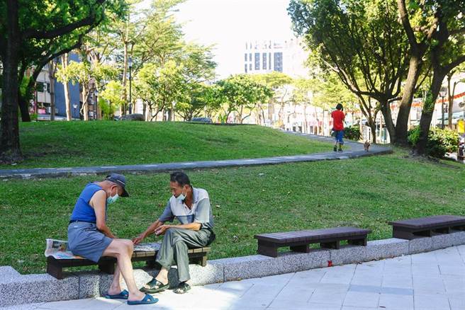 假日双连市场旁的公园，有人戴着口罩下棋。中央流行疫情指挥中心3日公布国内无新增死亡与本土案例，指挥官陈时中表示，目前疫情维持稳定，针对现行户外戴口罩的政策进行调整，位于空旷区域时可以免戴口罩。（邓博仁摄）

