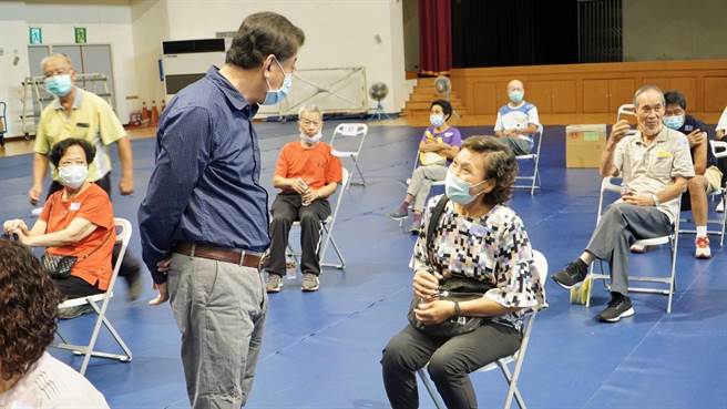 金湖鎮長陳文顧與接種莫德納疫苗的鄉親閒話家常，老人家感受溫馨關懷。（金湖鎮公所提供）