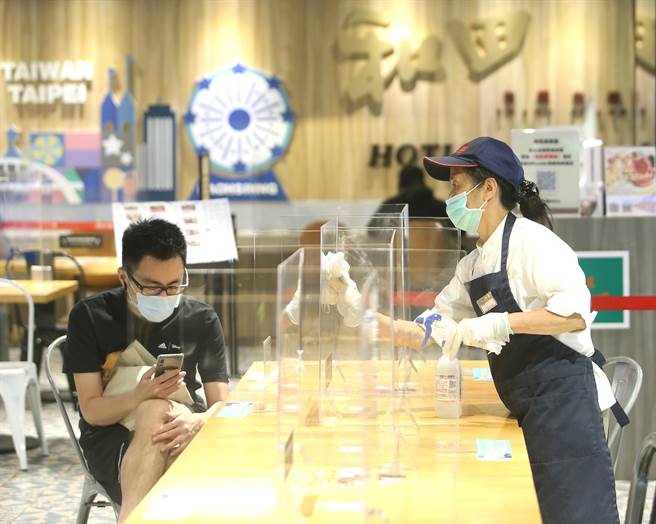 国内疫情趋缓，中央流行疫情指挥中心副指挥官陈宗彦4日宣布，餐饮场所用餐不限制使用隔板或维持1.5公尺间距，宴席开放离桌敬茶酒等社交活动，放宽桌菜及自助餐取菜等方式，下午华纳威秀商圈百货美食街清洁人员仍照防疫规定，定时消毒隔板与桌面，杜绝疫情产生。(陈怡诚摄)