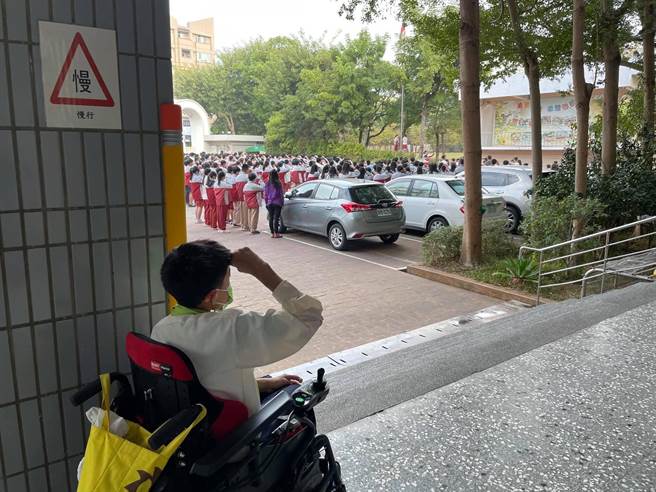 汉口国中3年级脑麻生施言道，克服先天上的障碍，仍坚持在走廊，跟全校同学同步升旗。（读者提供／张妍溱台中传真）