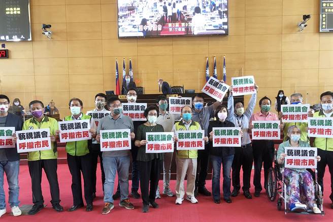 民進黨市議員蜂擁衝到主席台前，舉牌高喊「藐視議會，呼攏市民」抗議，場面脫序；主席急忙宣布休息10分鐘。（陳世宗攝）