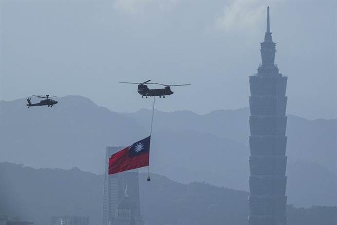 陆军契努克（CH-47SD）直升机吊挂国旗飞越台北市区，背景为台北101大楼。（黄子明摄）