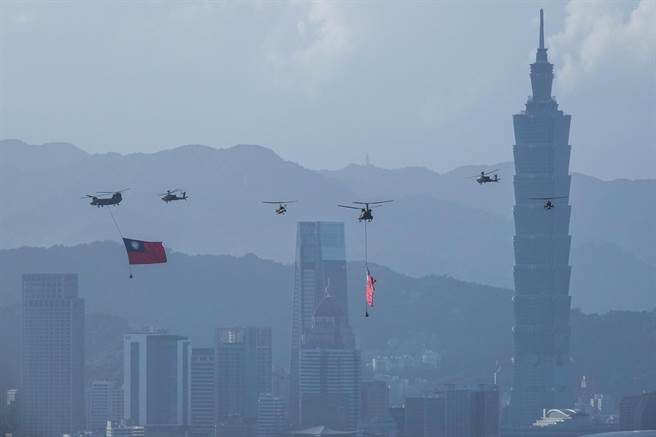 陆军契努克（CH-47SD）直升机吊挂国旗飞越台北市区，背景为台北101大楼。（黄子明摄）