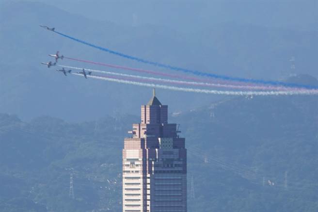 空军雷虎小组喷出彩色烟雾飞越总统府附近空域，背景为台北车站前新光三越大楼。（黄子明摄）