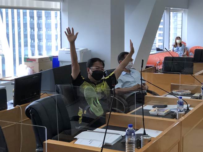 綠營市議員謝志忠表決台中購物節預算時，同時舉雙手及單腳強調他有3票。（陳世宗攝）