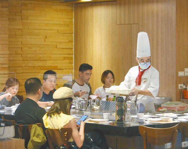 拿掉隔板、取消梅花座，随着餐饮内用放宽，业者乐观预估，可激励民眾进餐厅吃饭，桌转率可望提高。图为4日华纳威秀商圈百货公司铁板烧店用餐仍摆上隔板做好防疫工作。（陈怡诚摄）