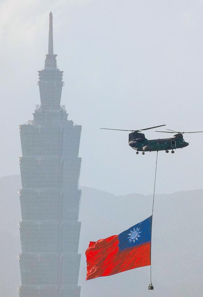 国防部长邱国正昨在立院受访表示，共军频繁扰台，对空军及海军部队确实造成很大压力。图为国庆国防军力展示空中分列式5日举行第三次预演，陆军契努克（CH-47SD）直升机吊挂国旗飞越台北市区，背景为台北101大楼。（黄子明摄）
