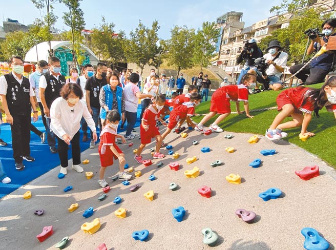 嘉義市中央廣場全齡遊戲場啟用，市長黃敏惠（白衣者）與小朋友開心衝上攀爬牆。（廖素慧攝）