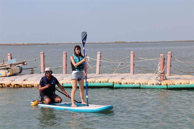 台南市七股生活艺术市集9日下午于南湾码头游憩区展开，游客下海体验SUP立式划桨。（刘秀芬摄）