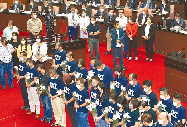 立法院8日总质询，当国民党团总召费鸿泰上台质询时，同党立委手持白色菊花为8百多位染疫过世的的民眾默哀，行政院长苏贞昌（右上）坐在座位上未有反应，民进党立委则围在旁保护。（姚志平摄）