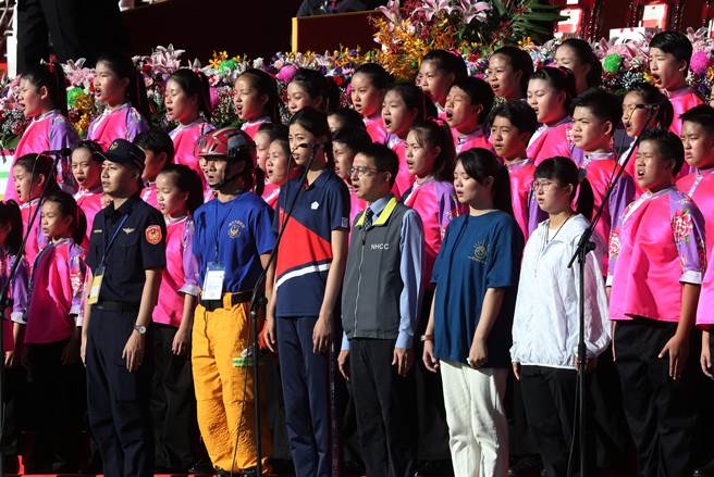 中华民国110年国庆大会10日在总统府前举行，典礼前，疾管署副署长罗一钧（右三）与奥运跆拳道铜牌得主罗嘉翎（右四）等六位各界英雄代表偕同国立客家儿童合唱团共同演练领唱国歌。（刘宗龙摄）
