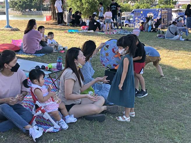 当地民眾带着小朋友吃美食、听音乐，在湖畔大草地说说笑笑，共享假期亲子同乐的美好时光。（李金生摄）