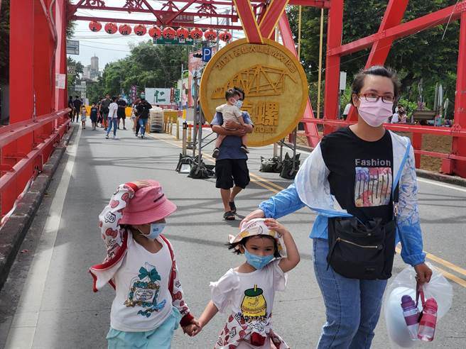 今天濁水溪畔風勢很強，西螺大橋文化節的遊客用手壓住帽子才能行走。（周麗蘭攝）