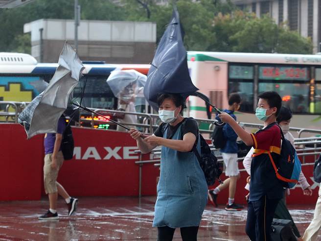 受到轻度颱风圆规外围环流影响，台北地区11日出现一阵阵的雨势及强风，突如其来的风势吹的路上行人伞花朵朵开。（刘宗龙摄）
