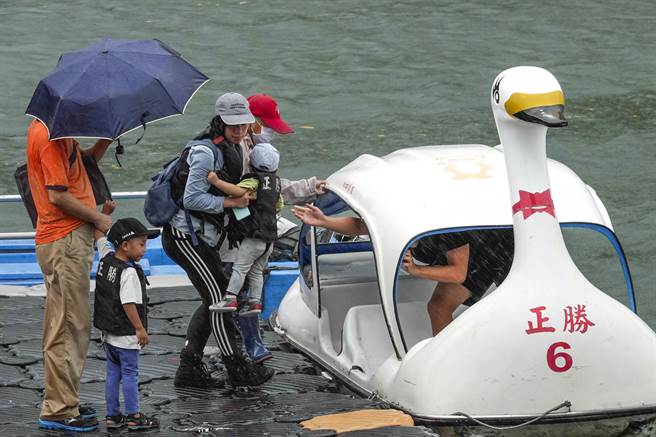 新北市碧潭风景区上午游客明显减少，少数到访民眾冒着间歇性大雨撑伞下水划船，游兴不减。（黄子明摄）