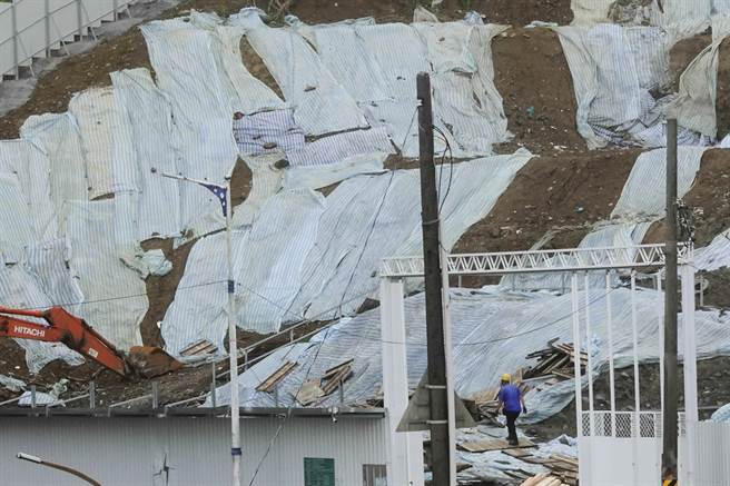 基隆市望海巷渔港旁一处施工中的山坡地盖满防水帆布，一名工人在工地巡视警戒。（黄子明摄）