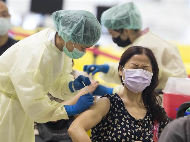 许多民眾12日按预约时程前往台北市花博争艳馆大型接种站施打，在接种时因感到疼痛而蹙起眉头。（杜宜谙摄）