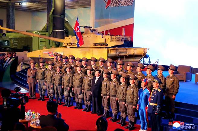 11日北韩国防展览会上，金正恩的风采被第一排右边穿着亮蓝色紧身衣的男子抢走。（图／路透社、北韩朝中社）